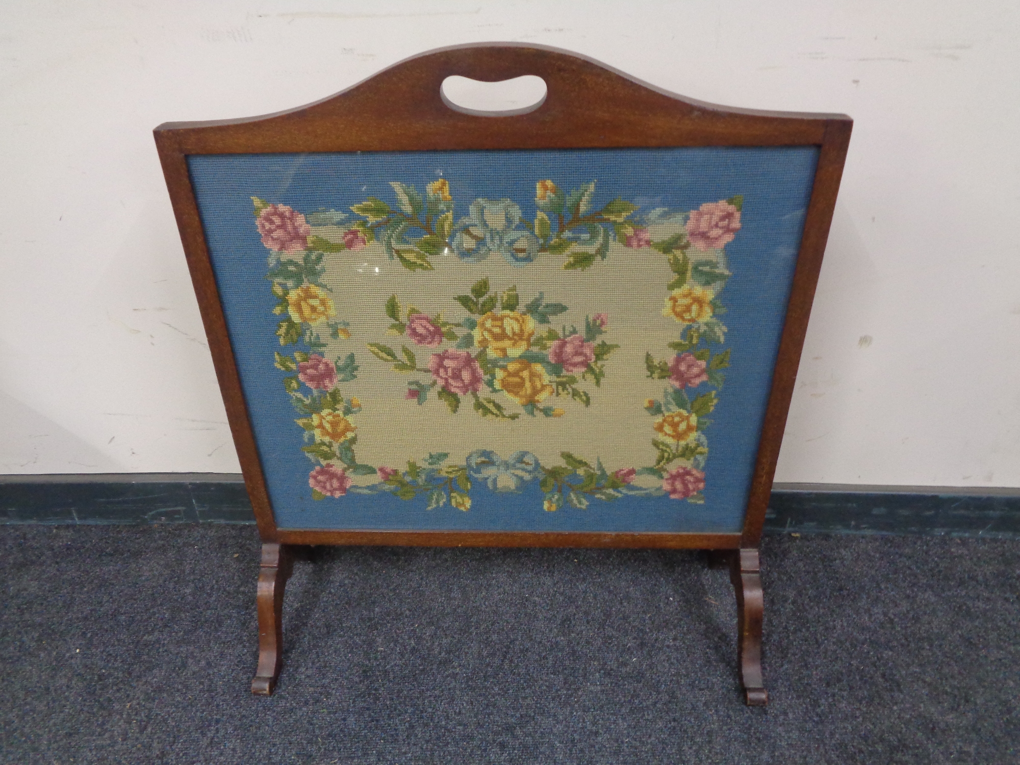 A mahogany embroidered fire screen