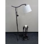 A contemporary metal floor lamp on tripod support together with a wrought iron companion set/