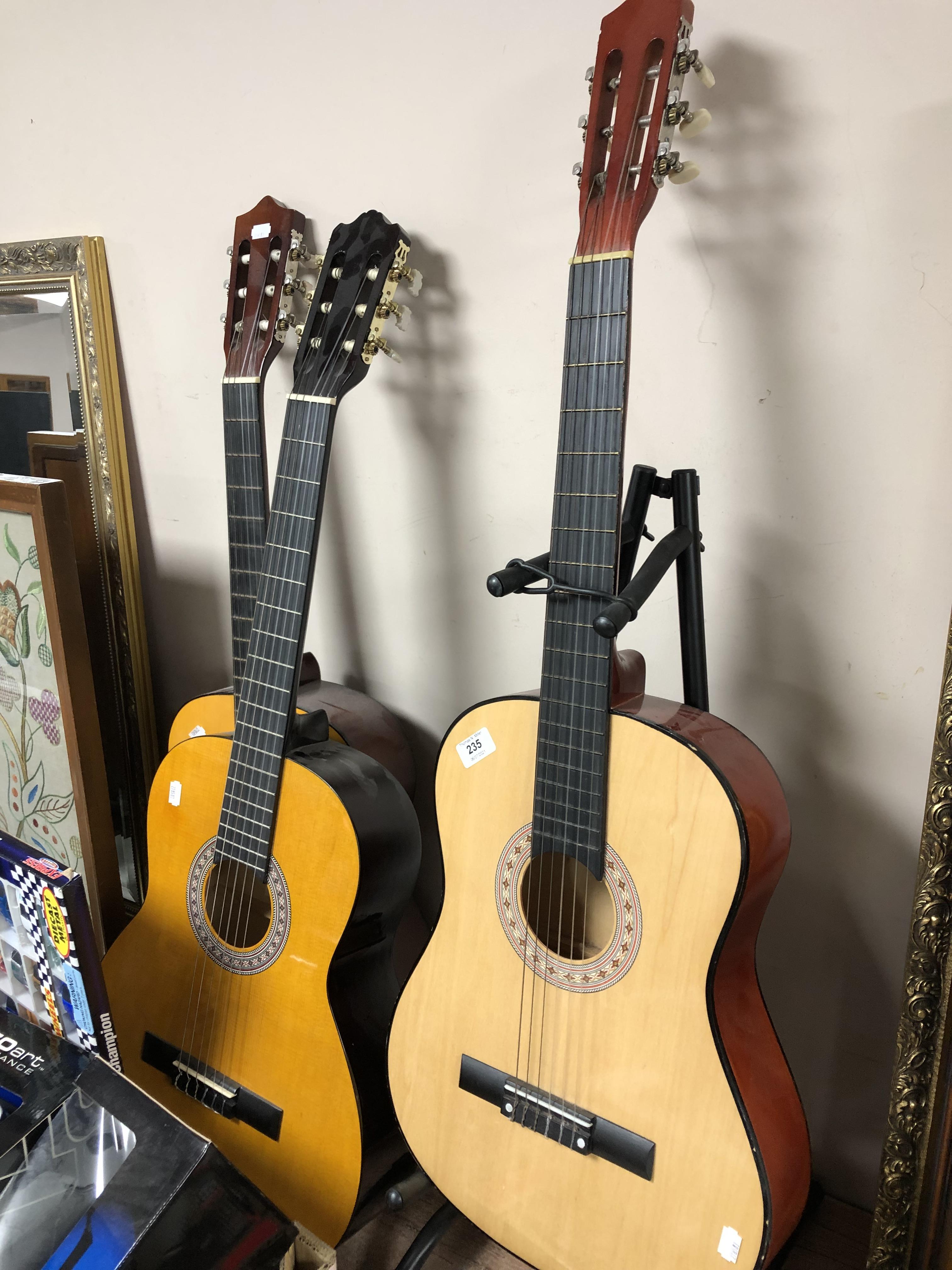 Three classical guitars together with a guitar stand.