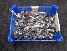 A crate containing a large quantity of loose stainless steel cutlery