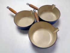 Three Le Creuset wooden handled saucepans.