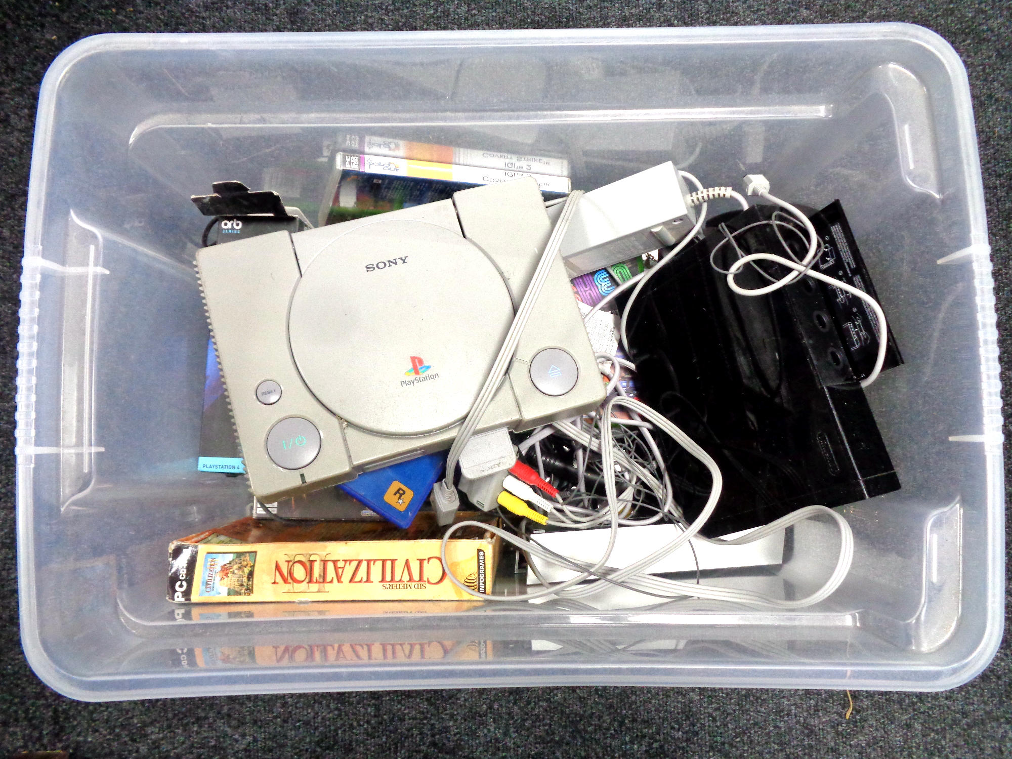 A box containing Sony PlayStation I, Nintendo Wii, various games, USB microphone.