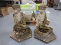 A pair of weathered concrete figures of seated children on hexagonal bases