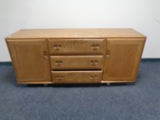 A low Ercol elm sideboard fitted two cupboard doors and three central doors