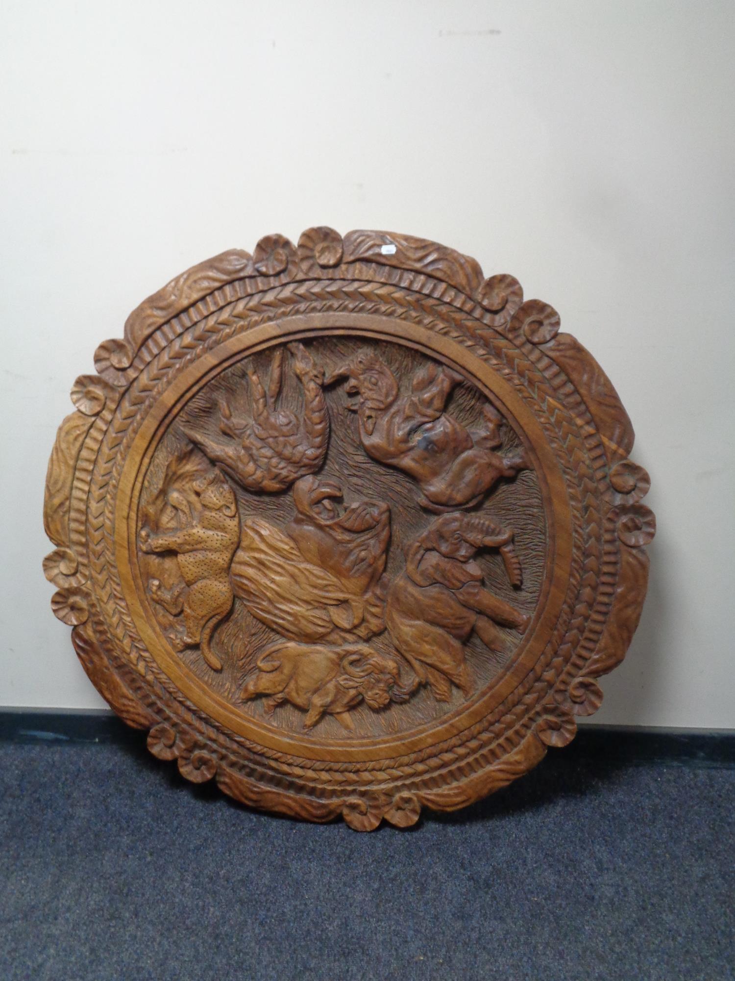 A heavily carved shaped African coffee table depicting animals on elephant supports