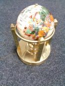 A six inch gemstone globe rotating clock on brass stand