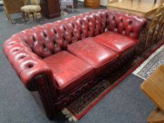 A three seater red button leather Chesterfield settee
