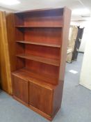 A mid 20th century teak triple section bookshelf fitted cupboard beneath