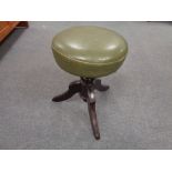 An antique mahogany revolving stool upholstered in a green leather