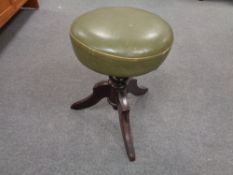 An antique mahogany revolving stool upholstered in a green leather