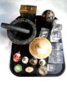 A tray containing glass paperweights, decorative eggs on stands, marble pestle and mortar,