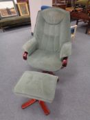 A stained beech swivel armchair upholstered in green dralon with matching stool