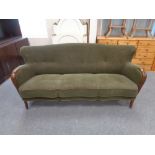 A mid 20th century wood armed three seater settee upholstered in a green button back fabric