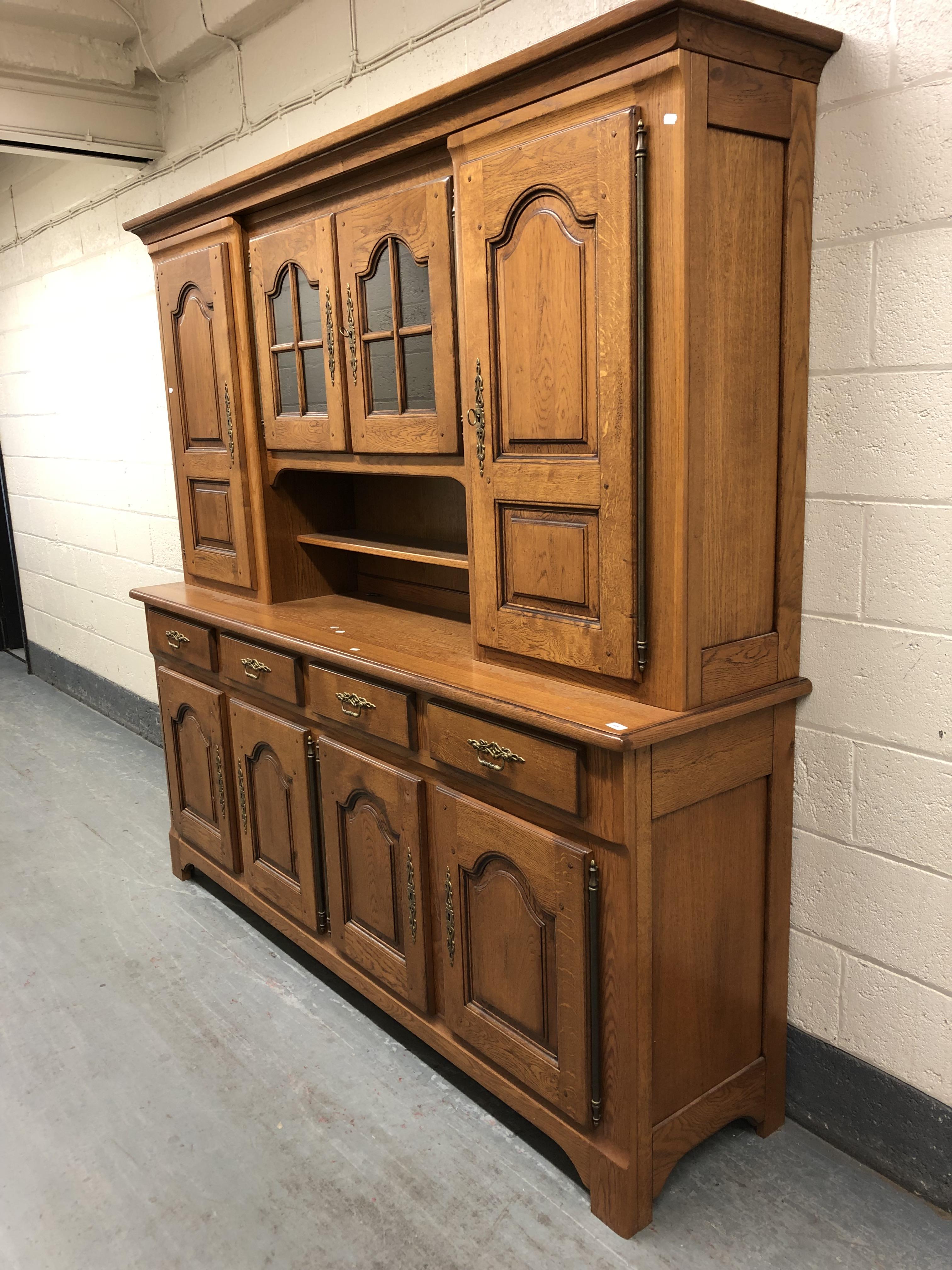 A 20th century oak dresser fitted eight cupboards and four drawers with brass bow handles,