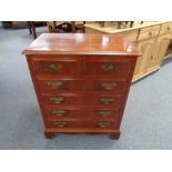 A Georgian style six drawer chest with brass drop handles in a mahogany finish