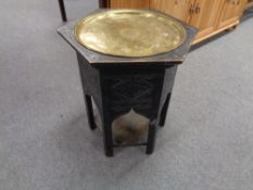 A hexagonal ebonised eastern occasional table with brass lift out tray