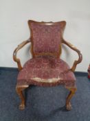 An antique walnut framed armchair on claw and ball feet upholstered in a red brocade fabric