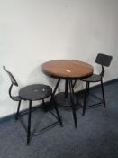 A circular pine topped bistro style table on metal base together with two chairs