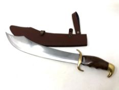 A wood and brass hilted hunting knife, with curved blade, in sheath.