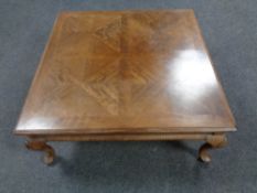 A contemporary square coffee table on cabriole legs in walnut finish