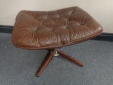 A 20th century brown button leather footstool on four way pedestal