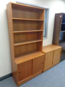 A set of mid 20th century teak open bookshelves fitted double door cupboard beneath together with a