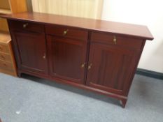 A contemporary triple door sideboard fitted three drawers above in a mahogany finish
