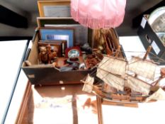 A box containing brass table lamp with shade, wooden animal ornaments, wooden model of a galleon,