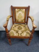 An antique armchair upholstered in a green and gold brocade fabric