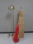 A wicker floor lamp together with a further brass floor lamp and a conical table lamp