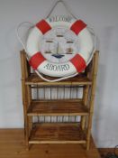 A bamboo three tier shelving unit together with a life buoy bearing nautical knots