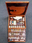 An artist's box with brass handles and mounts containing oil paints and painting supplies