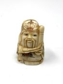 A carved Chinese bone netsuke - Gentleman holding a club