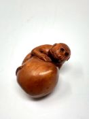 A carved Chinese hardwood netsuke - Monkey on fruit