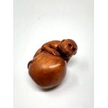 A carved Chinese hardwood netsuke - Monkey on fruit