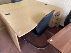 A three drawer oak effect desk, width 160 cm together with a black leather chair.