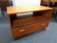 A 20th century G-Plan teak entertainment stand fitted a drawer and slide, on castors,