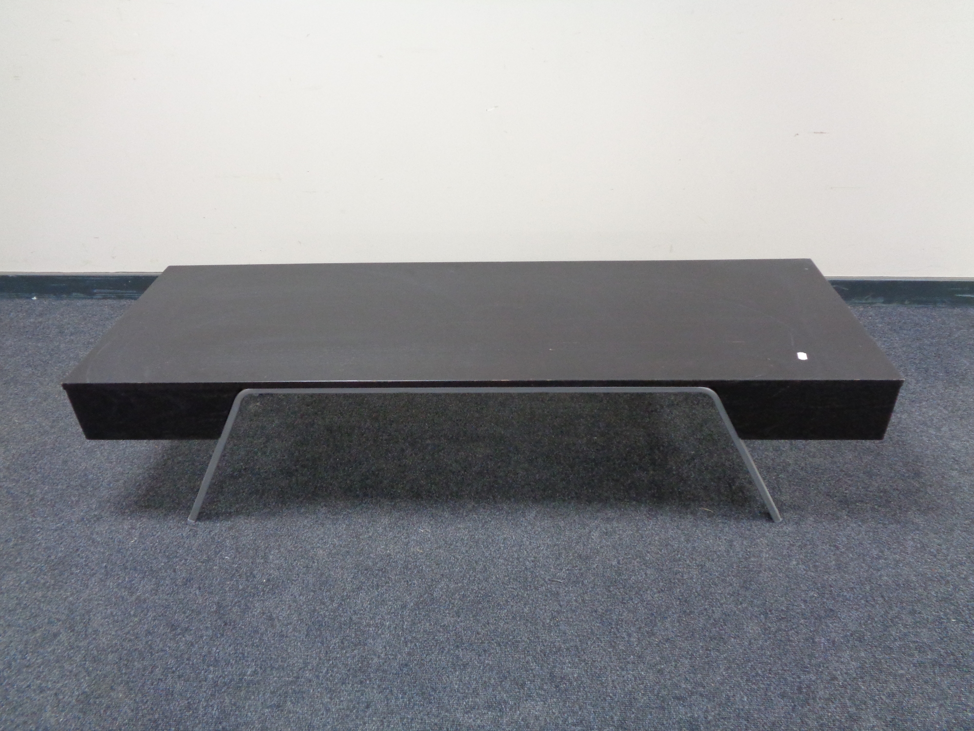 A rectangular contemporary black ash coffee table on metal legs.