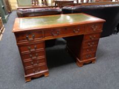 A reproduction twin pedestal desk fitted eleven drawers with green tooled leather inset panel