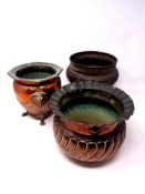 Two antique copper plant pots, one on raised feet,