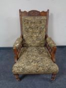 An Edwardian carved beech gentleman's armchair upholstered in a buttoned tapestry fabric,