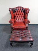 A Chesterfield red buttoned leather wingback armchair with matching stool
