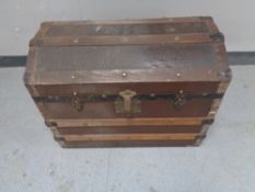 An antique wooden bound dome topped shipping trunk