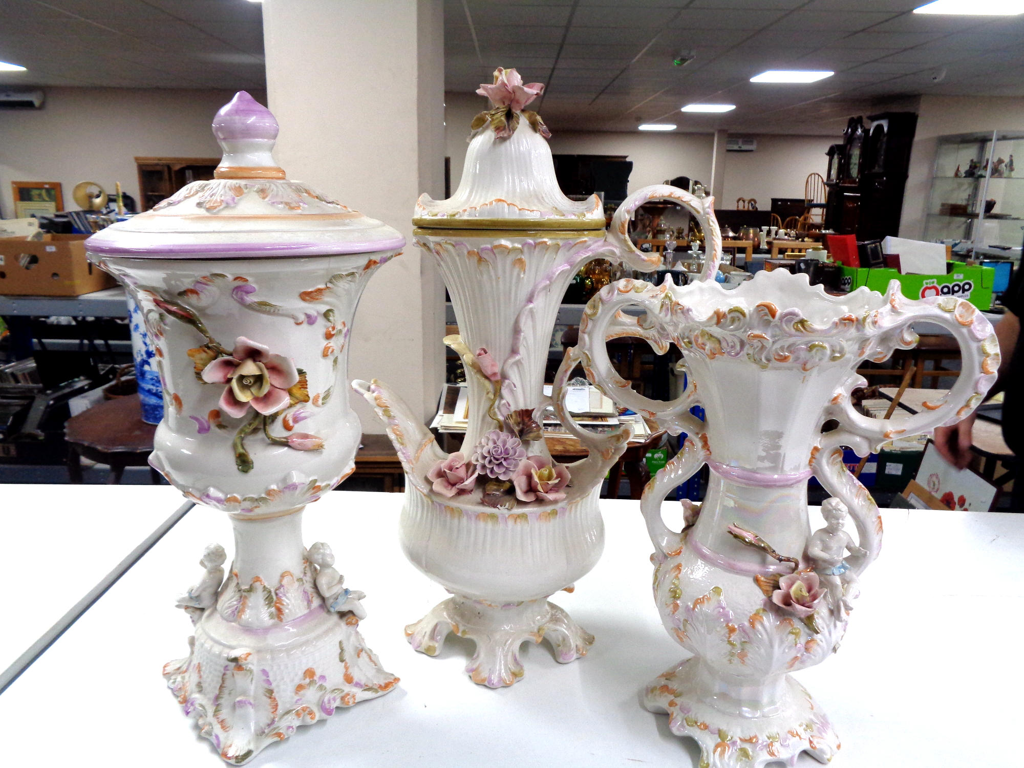 A three piece glazed pottery flower encrusted set to include lidded vase,