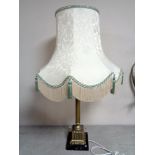 A brass Corinthian column table lamp with shade on a square marble base