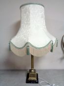 A brass Corinthian column table lamp with shade on a square marble base