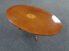 An inlaid oval pedestal coffee table.