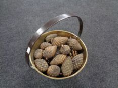 An antique brass cast iron handled jam pan containing pine cones