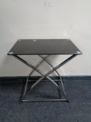 A contemporary glass topped occasional table on metal X-framed support