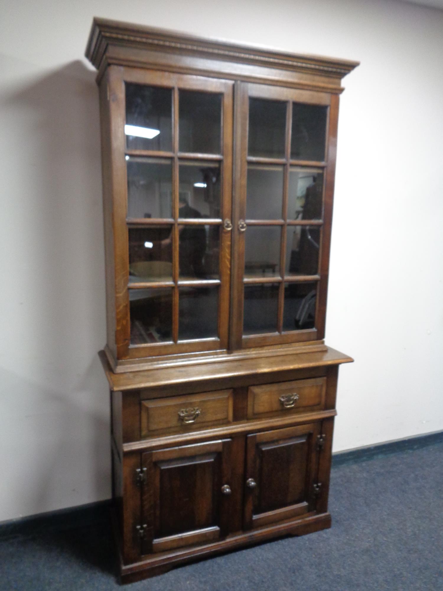 A good quality oak double door glazed bookcase with cupboards and drawers beneath,